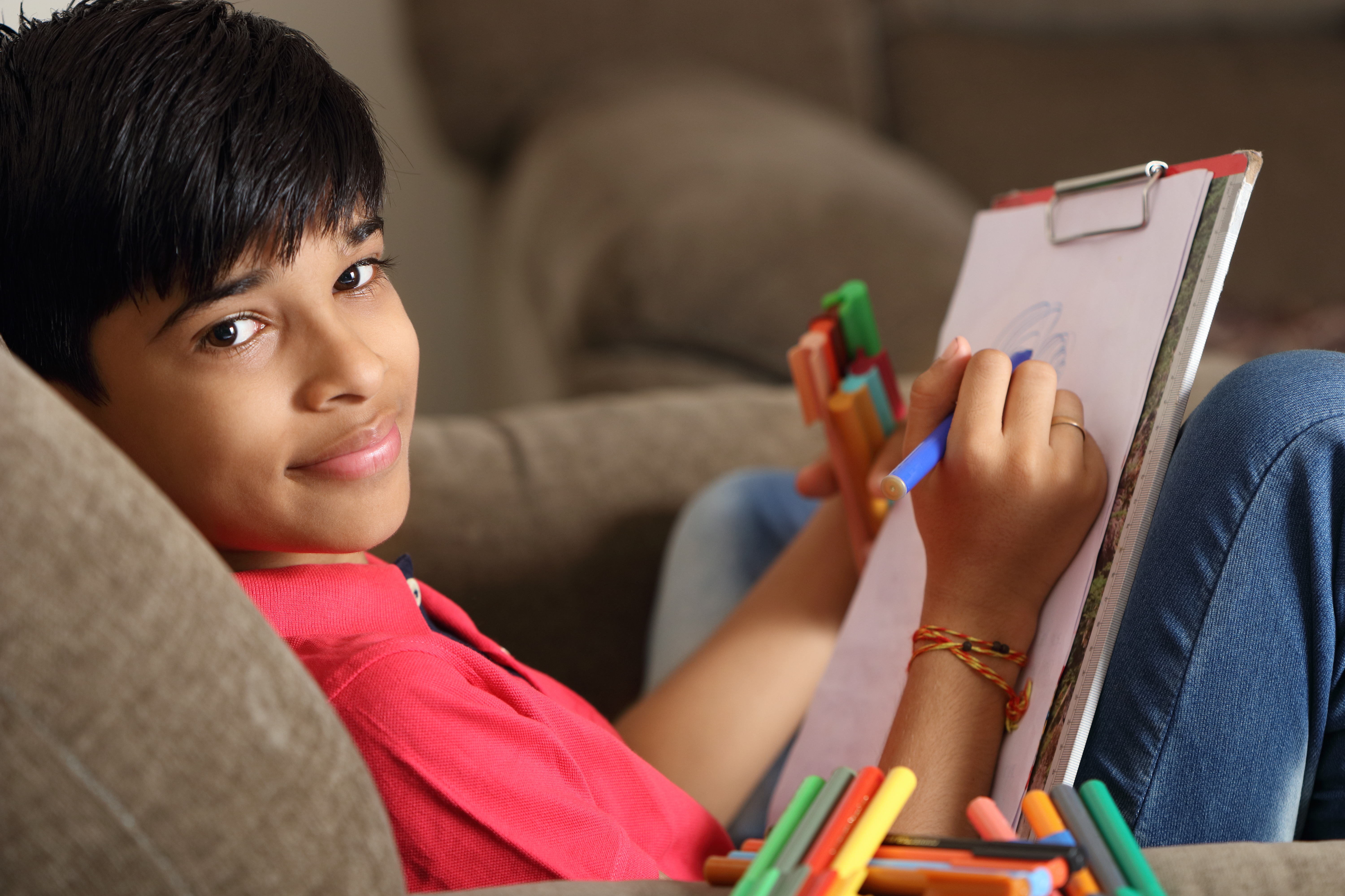 Young boy sitting on the couch colouring