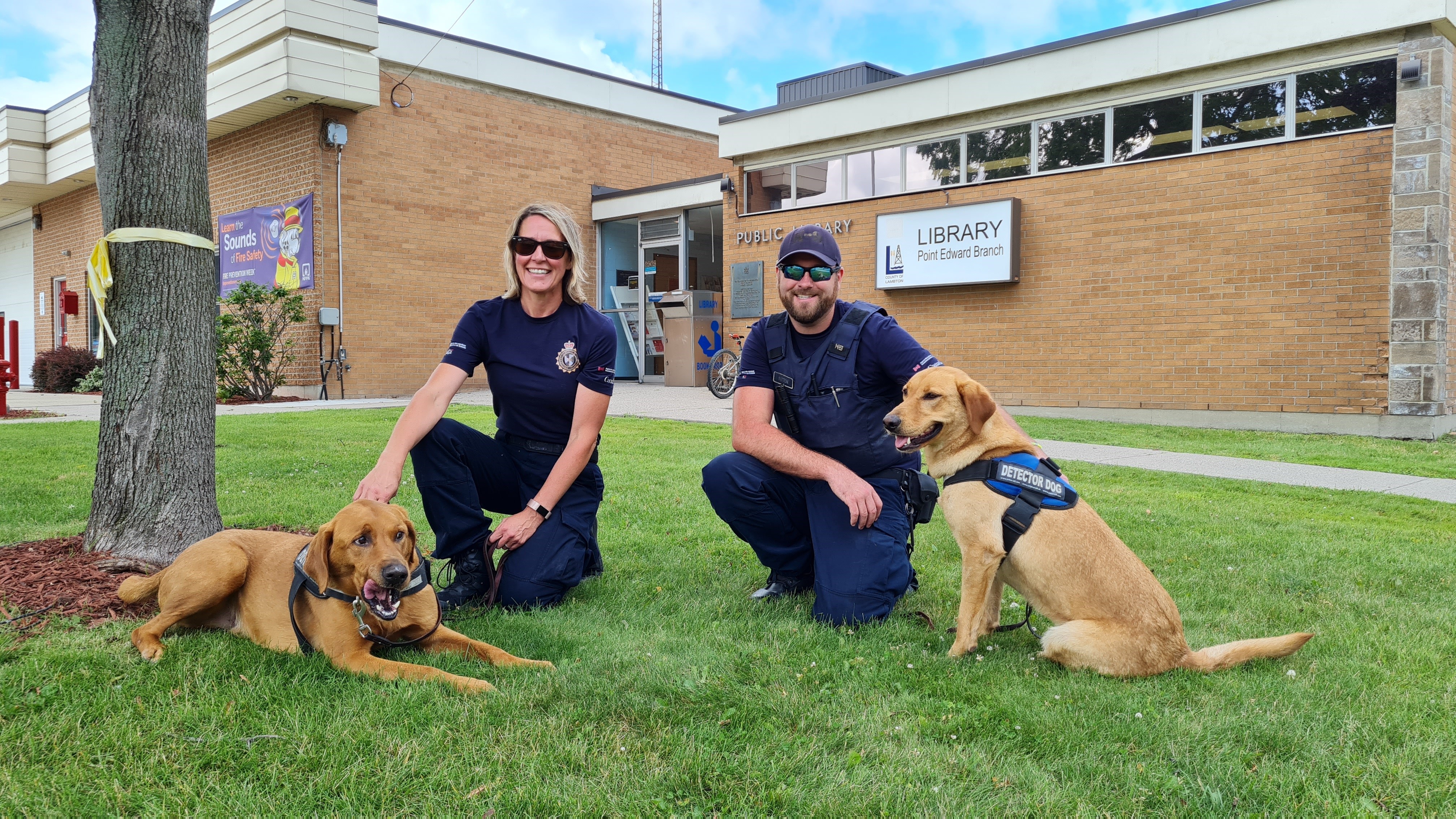 two officers with their police dogs in front of Point Edward Library